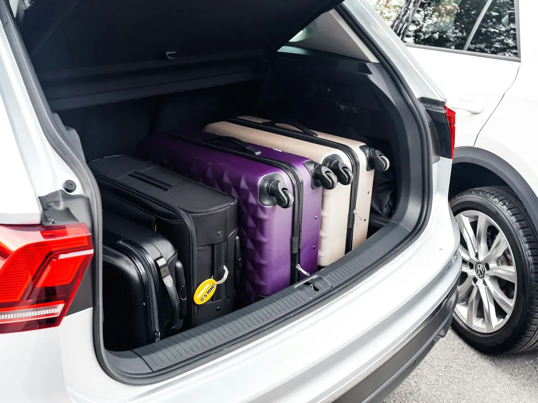 Four suitcases packed into the open back of an estate car.